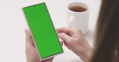 Yeşil ekran krom tuşlu akıllı telefonu olan bir kadın sosyal medyada ya da internet dükkanında arama yapıyor. İnternet, iletişim kavramı kapanıyor. Yüksek kalite 4k görüntü