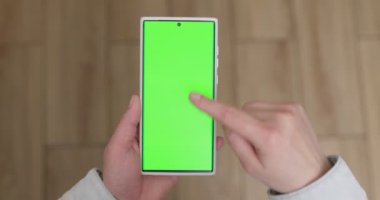 Woman with green screen chroma key smartphone scrolling through social media or online shop - internet, communications concept close up. High quality 4k footage