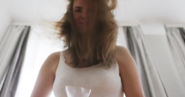 Όμορφη Νεαρή Γυναίκα Που Χρησιμοποιεί Στεγνωτήρα Μαλλιών Κοντά Στο Παράθυρο — Αρχείο Βίντεο