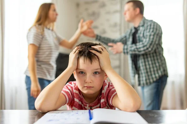 A son feels frustrated while his parents fight in the background. Family conflicts or divorce impact on on child development