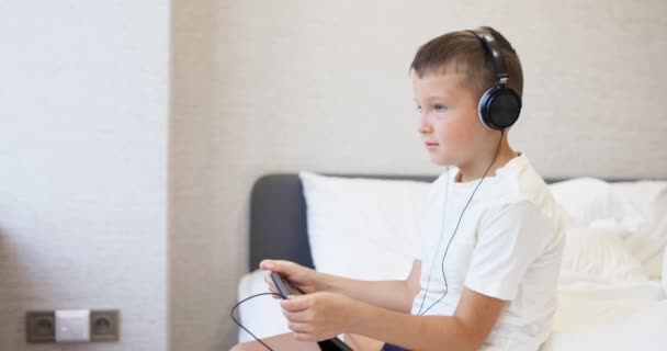 Ένα Παιδί Αγόρι Λευκό Shirt Χρησιμοποιώντας Tablet Υπολογιστή Ακουστικά Κάθεται — Αρχείο Βίντεο
