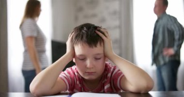 Üzgün bir çocuk ebeveynleri arasındaki bir tartışma sırasında elleriyle kulaklarını kapatır. Aile içi anlaşmazlıklar ya da boşanmanın çocuk gelişimi üzerindeki etkisi