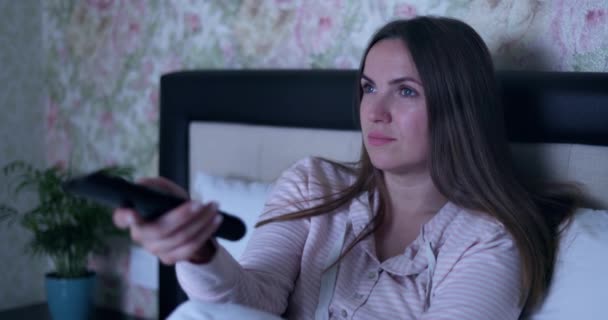 Das Auf Dem Bett Liegende Mädchen Schaltet Mit Der Fernbedienung — Stockvideo