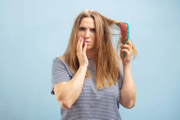 一个有梳子的年轻女人对她的头发问题很不高兴 — 图库照片
