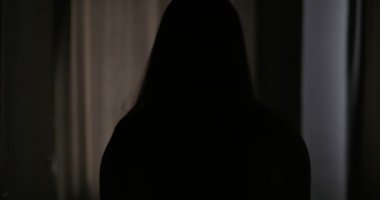 Güzel, genç esmer kadın, sabah güneşinin rahat dairesini aydınlatması için perdeleri açıyor. Kadın perdeleri açıyor ve gün ışığının tadını çıkarıyor. Yüksek kalite 4k görüntü