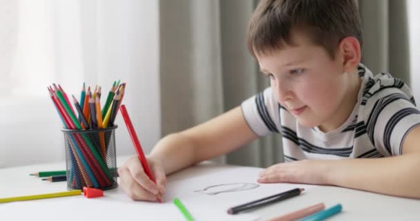 Ένα Παιδί Ζωγραφίζει Λευκό Χαρτί Χρωματιστά Μολύβια Ενώ Κάθεται Ένα — Αρχείο Βίντεο