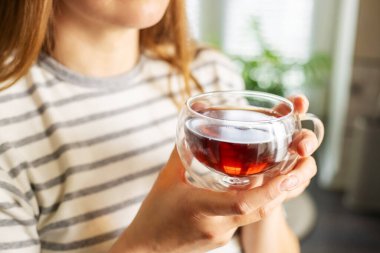 Kadınların elleri sabahları bir fincan sıcak çay tutuyor. Genç bir kadın elindeki çayı rahatlatıyor. Çay konseptiyle günaydın.