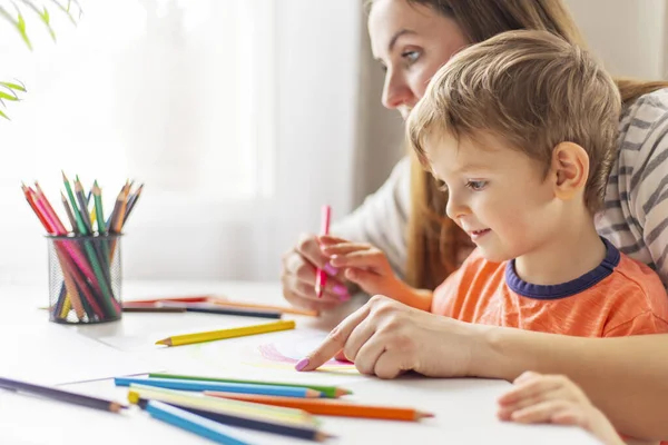 stock image Mother and child drawing with pencils sitting at the desk at home. Happy family