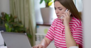Gülümseyen güzel bir kadın müşterisiyle akıllı telefon görüşmesi yapıyor, profesyonel danışmanlık veya tavsiye veriyor, evde dizüstü bilgisayarla çalışırken satışları uzaktan yapıyor.