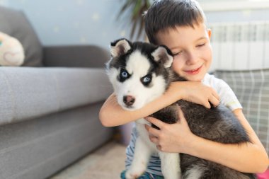 İri köpeğiyle yerde oturan bir çocuk. Çocuk yavrusunu kucaklıyor. Hayvan bakımı. Doğum günü Sürprizi