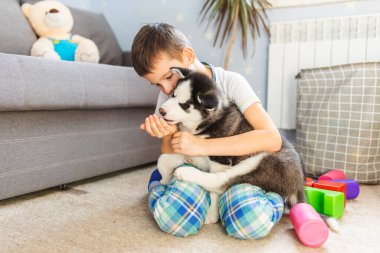 İri köpeğiyle yerde oturan bir çocuk. Çocuk yavrusunu kucaklıyor. Hayvan bakımı. Doğum günü Sürprizi