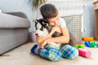 İri köpeğiyle yerde oturan bir çocuk. Çocuk yavrusunu kucaklıyor. Hayvan bakımı. Doğum günü Sürprizi