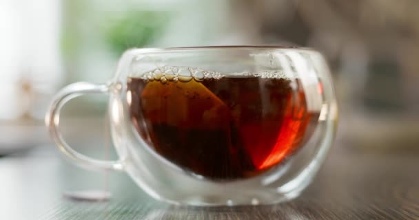 閉じるまで熱いお茶をカップ蒸し キッチンの木製テーブルの上で煙とガラスカップで熱いお茶 熱いお茶を飲む概念 高品質4K映像 — ストック動画