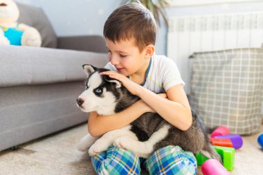 İri köpeğiyle yerde oturan bir çocuk. Çocuk yavrusunu kucaklıyor. Hayvan bakımı. Doğum günü Sürprizi