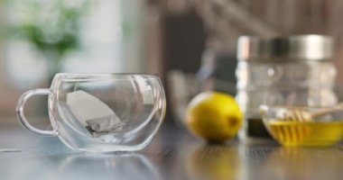 Siyah çay poşetli cam bardak. Sabah çayı yapıyorum. Çay poşetini sıcak suyla dolu bir fincana koyuyorum. Yüksek kalite 4k görüntü