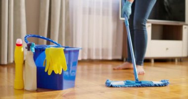 Günlük kıyafetli bir kadın, ıslak bir mikrofiber paspas ile ahşap bir zemini yıkıyor, ev ödevi yapıyor, rutin temizlik, temizlik konsepti. Yüksek kalite 4k görüntü