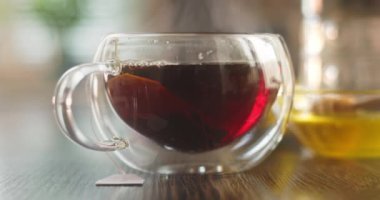 Yakın plan sıcak çay fincanı. Mutfaktaki ahşap masada dumanlı cam bardakta sıcak çay. Sıcak çay içeceği konsepti. Yüksek kalite 4k görüntü