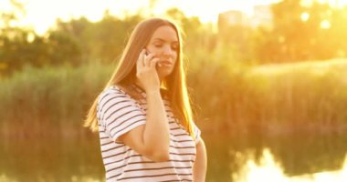 Genç, güzel bir kadın telefonda arkadaşlarıyla konuşuyor. Parkta gülüp eğleniyorlar. Yüksek kalite 4k görüntü