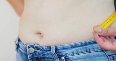 Kilolu bir kadın, ölçü bandıyla belini ölçüyor. Aşırı kilolu, aşırı beslenme konsepti. Yüksek kalite 4k görüntü