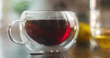 Yakın plan sıcak çay fincanı. Mutfaktaki ahşap masada dumanlı cam bardakta sıcak çay. Sıcak çay içeceği konsepti. Yüksek kalite 4k görüntü