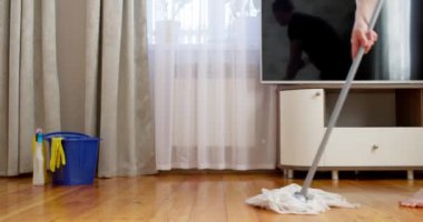 İyimser erkek paspasla dans ediyor ve temizlik sırasında eğleniyor. Neşeli adam ev işlerini seviyor, yaratıcı bir şekilde ev temizliği yapıyor. Yüksek kalite 4k görüntü