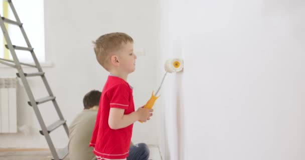 子供たちは ペイントローラーとブラシで壁をペイント 兄弟は熱心に白い壁をペイント 家族の修理アパートの家 高品質4K映像 — ストック動画