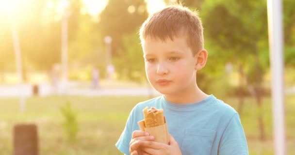 Junge Isst Ein Hot Dog Sandwich Park Bei Sonnenuntergang Freien — Stockvideo