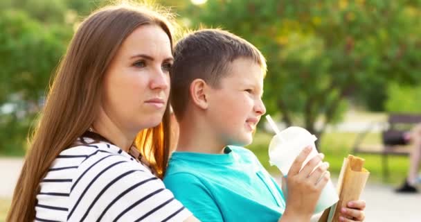 孩子和妈妈一起在公园里玩得很开心 孩子吃着热狗 喝着奶昔 高质量的4K镜头 — 图库视频影像