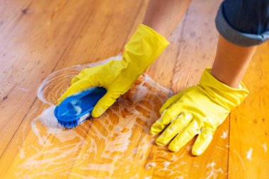 Lastik eldivenli kadın yerleri temizlemek için yer fırçası kullanıyor. Oda servisi ve temizlik konsepti.