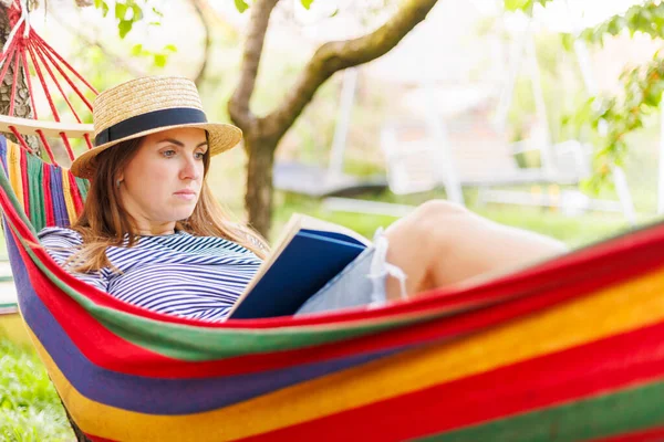 Jonge Vrouw Lezen Boek Terwijl Liggend Comfortabele Hangmat Groene Tuin — Stockfoto