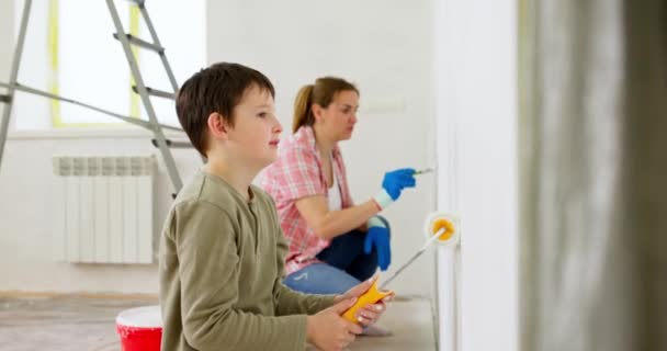 母親と彼女の息子は自宅でペイントローラーやブラシで壁を塗装し 一緒に改装を楽しんでいます 家族の時間だ 宿泊施設と家族のコンセプト 高品質4K映像 — ストック動画