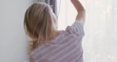 Genç bir kadın uzun saçını elektrikli saç kurutma makinesiyle kurutuyor. Yüksek kalite 4k görüntü