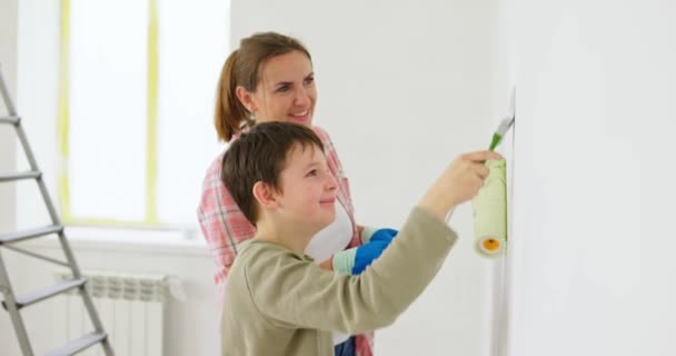 妈妈和她的儿子在家里用漆辊和刷子刷墙 享受着装修的乐趣 和家人在一起住房和家庭概念 高质量的4K镜头 — 图库视频影像