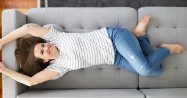 Mutlu pozitif kadın hafta sonu dinlenirken rahat kanepeye uzandı. Kadın evde huzurlu bir hafta sonu istirahatinin tadını çıkarıyor. Yüksek kalite 4k görüntü