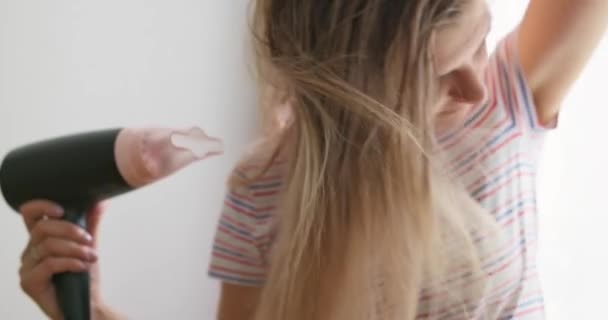 Seorang Wanita Muda Mengeringkan Rambut Panjangnya Dengan Pengering Rambut Listrik — Stok Video