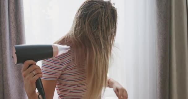 Seorang Wanita Muda Mengeringkan Rambut Panjangnya Dengan Pengering Rambut Listrik — Stok Video