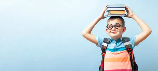 Mavi Arka Planda Elinde Kitaplarla Gözlüklü Komik Gülümseyen Okul Çocuğu — Stok fotoğraf