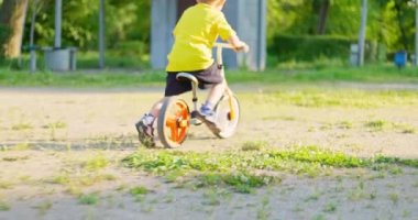 Şehir parkında bisiklet süren bir çocuk. Yaz tatiline. Çocuk dışarıda bisiklet sürmeyi seviyor. Boş zamanlarında çocuklar. Yüksek kalite 4k görüntü
