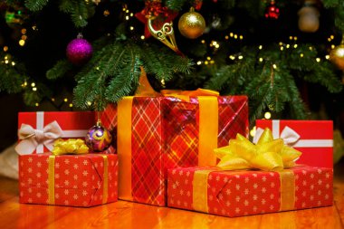 İçerideki güzel Noel ağacının altında yerde bir yığın Noel hediyesi kutusu var.