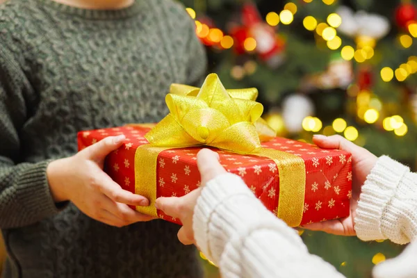 クリスマスツリーの背景に子供にクリスマスプレゼントを与える親の手 クリスマスのコンセプト — ストック写真