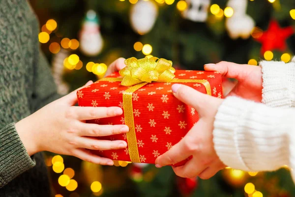 クリスマスツリーの背景に子供にクリスマスプレゼントを与える親の手 クリスマスのコンセプト — ストック写真