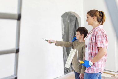 Mutlu bir aile babası ve çocuğu. Duvarı silindir ve fırçayla boyuyor. Dairede tamirat var.