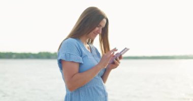 Cep telefonuyla mesaj atan ya da sahilde internette gezinen bir kadın. Kumsalda akıllı telefon kullanan bir kadın. Yüksek kalite 4k görüntü