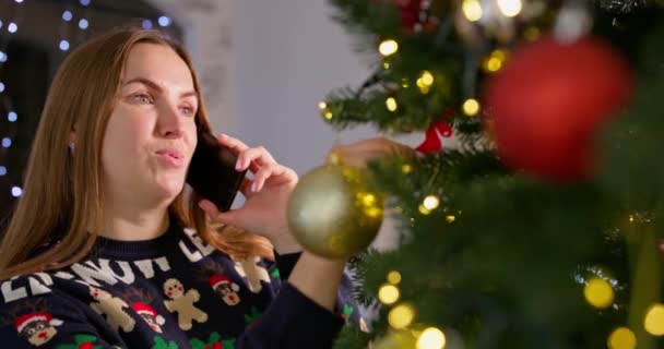 Молодая Женщина Украшает Елку Разговаривая Мобильному Телефону Друзьями Родственниками Уютной — стоковое видео