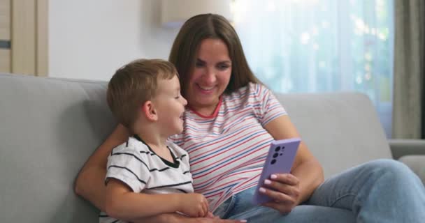여자와 그녀의 아들은 스마트 아늑한 소파에 가족은 스마트 사용하여 집에서 — 비디오