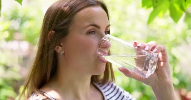 炎炎夏日 一个口渴的女人在花园里用玻璃杯喝水 女人喝着一杯水 健康的身体护理 高质量的4K镜头 — 图库视频影像