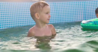 Çocuklar güneşli yaz gününde havuzda oynarlar, havuz eğlencesi. Yüksek kalite 4k görüntü