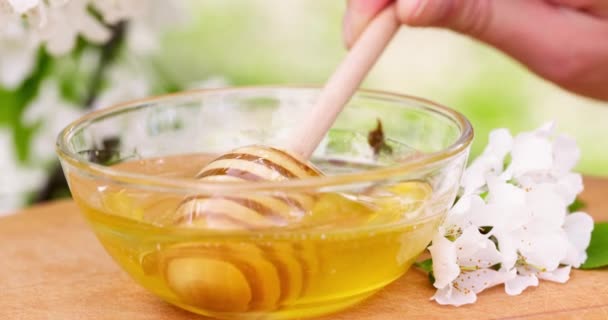 蜂蜜は 木製のテーブルの上にガラスボウルに蜂蜜のディップから滴り落ちる 健康的な有機厚さの蜂蜜は 木製の蜂蜜スプーンから浸漬 高品質4K映像 — ストック動画