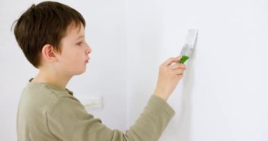 Apartmanda tamirat var. Mutlu çocuk boya fırçasıyla duvarı beyaz boyayla boyuyor. Yüksek kalite 4k görüntü