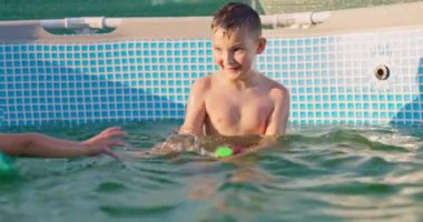 Çocuklar güneşli yaz gününde havuzda oynarlar, havuz eğlencesi. Yüksek kalite 4k görüntü